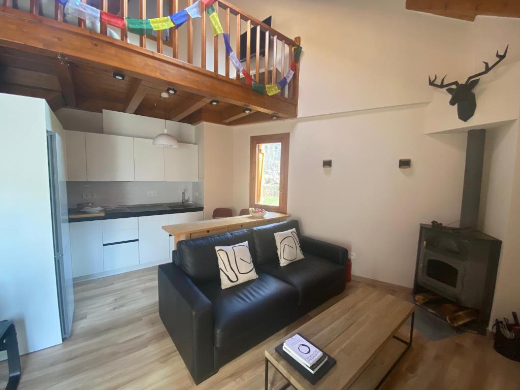 a living room with a black leather couch and a kitchen at Duplex Kasares en Sesué No VU HUESCA24037 in Sesué