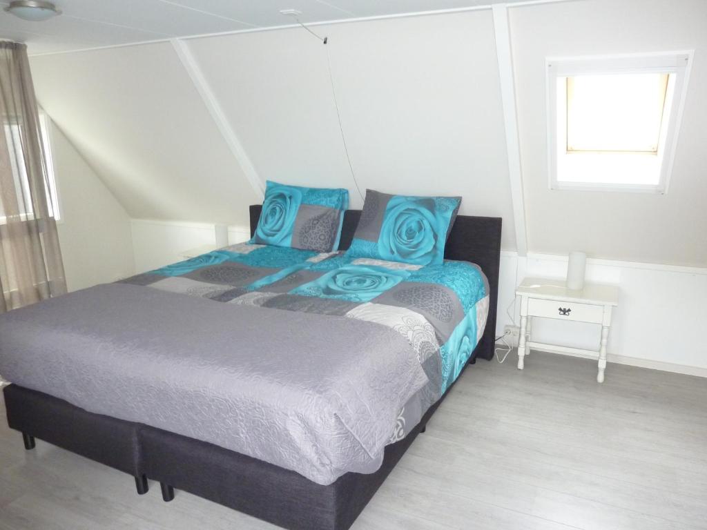 um quarto com uma cama grande e almofadas azuis em B&B It Lytshûs em Earnewâld