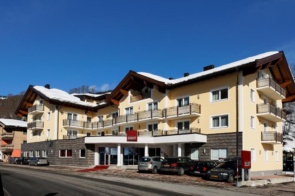 a large building with cars parked in front of it at Hotel Auwirt Zentrum in Saalbach Hinterglemm