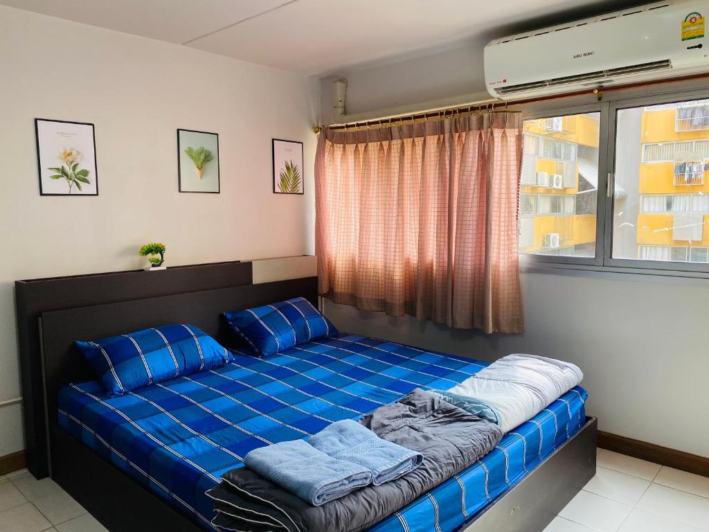 a bed with blue pillows in a room with a window at Condo popular T8 fl.9.2 in Thung Si Kan