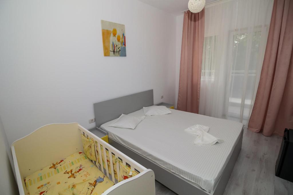 a small bedroom with a white bed and a crib at Hotel Atlantis in Eforie Nord