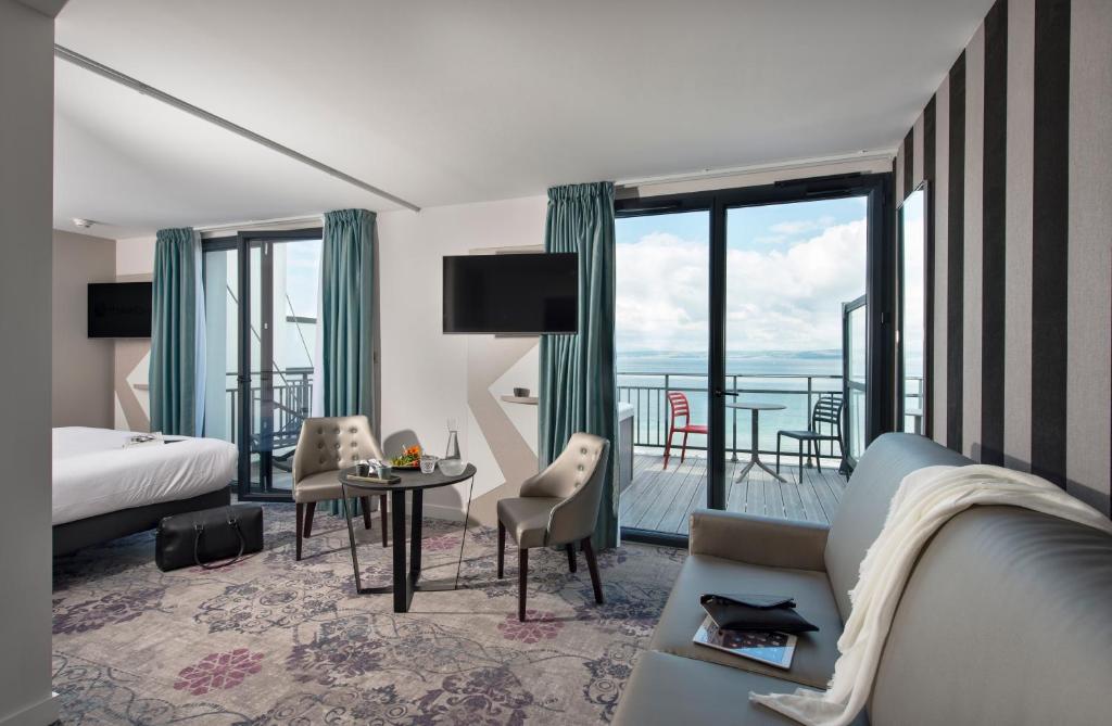 een hotelkamer met een kingsize bed en een balkon bij Hôtel Valdys Thalasso & Spa - la Baie in Douarnenez