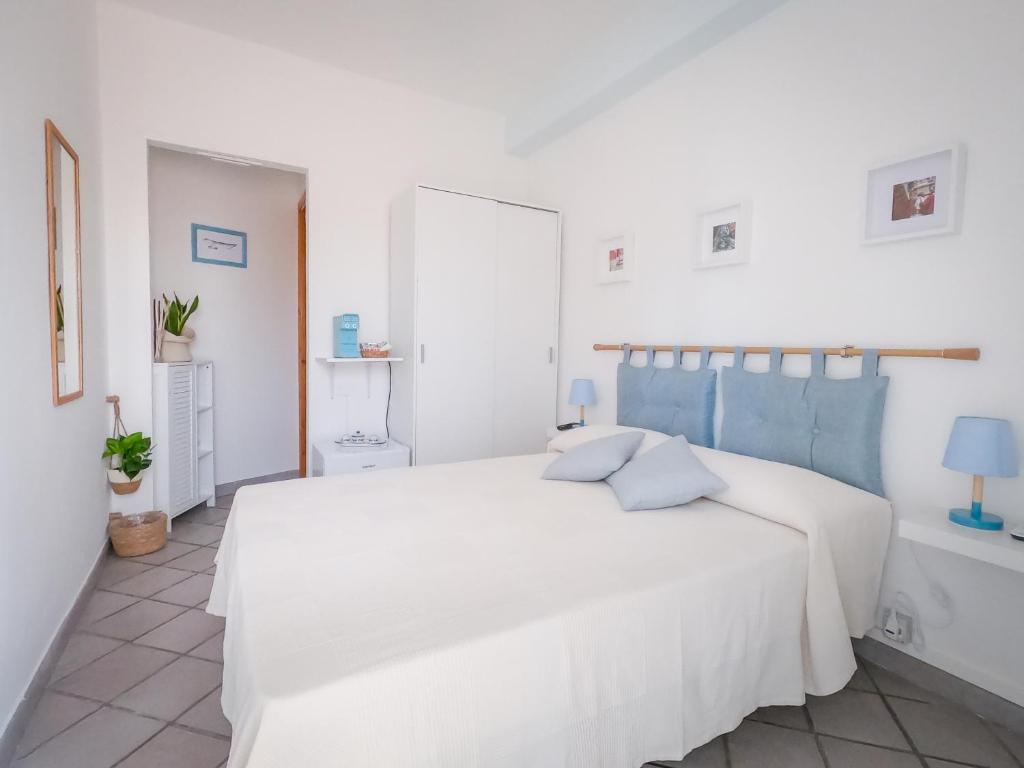 una camera da letto bianca con un grande letto bianco con accenti blu di A 50 scalini dal mare - Camera Doppia Privata a Maratea
