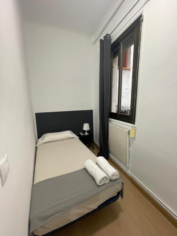 um pequeno quarto com uma cama e uma janela em Toledo habitaciones em Madri