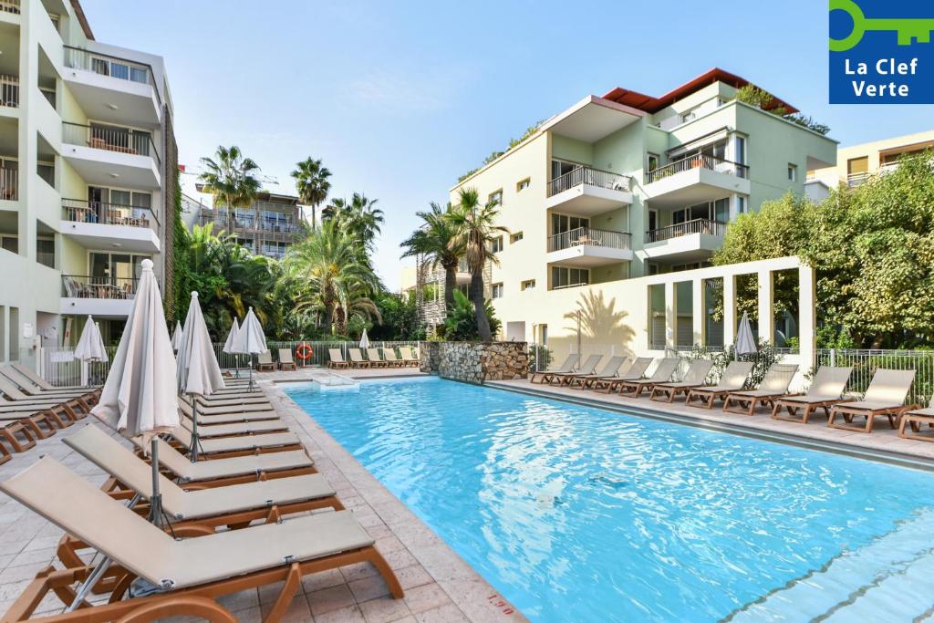 a swimming pool with chaise lounges and chairs next to buildings at Résidence Pierre & Vacances Premium Port Prestige in Antibes