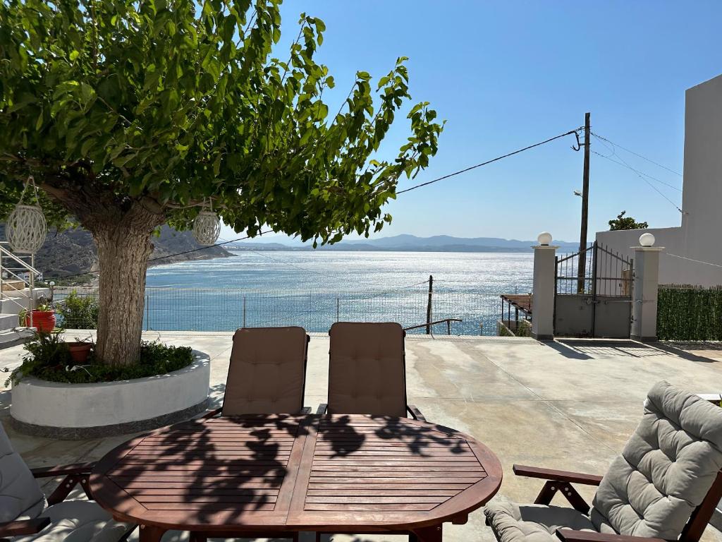 een houten tafel en stoelen met uitzicht op het water bij Irini Panorama in Agia Galini