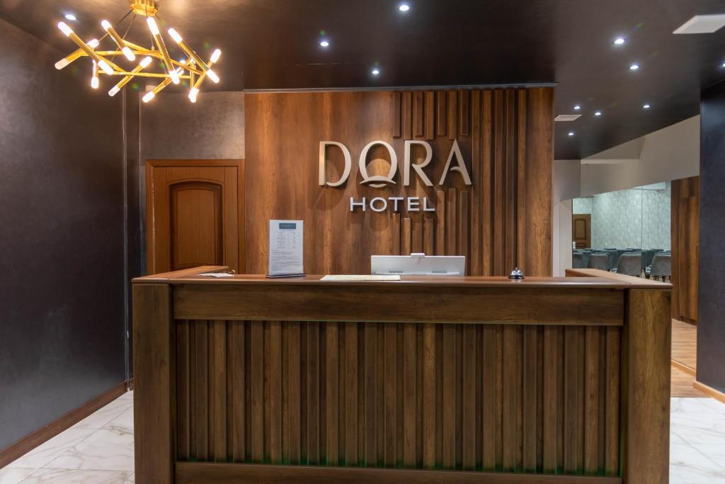 a hotel reception desk with a darra hotel sign at Dora Hotel in Shymkent