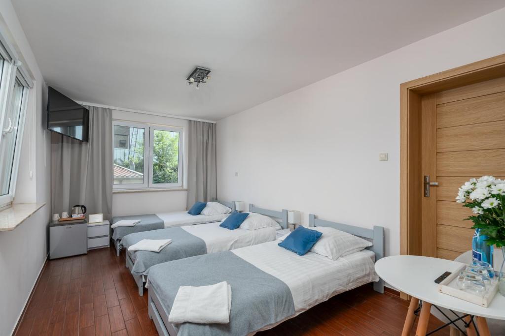 una camera d'albergo con tre letti e un tavolo di Sleeply Pensjonat Złotniki a Breslavia