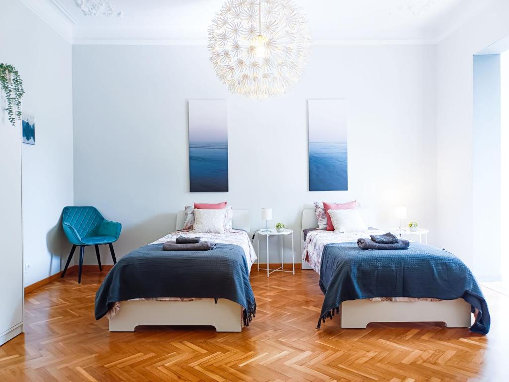 2 Betten in einem weißen Zimmer mit Kronleuchter in der Unterkunft By La Pedrera - Diagonal Rooms in Barcelona