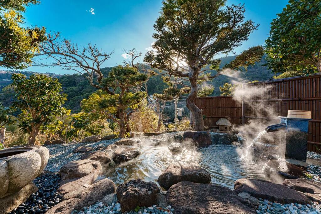 uma fonte de água num jardim com pedras e árvores em VILLA ATAMI -Nagomi- em Atami