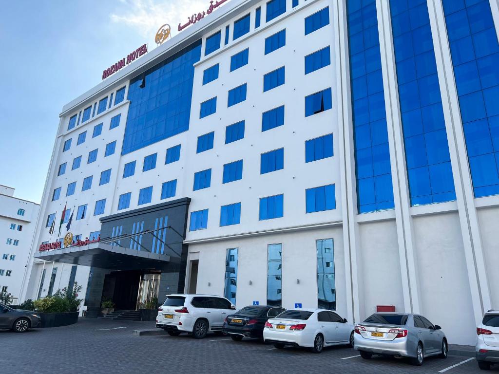 ein großes Gebäude mit Autos auf einem Parkplatz in der Unterkunft ROZANA HOTEL in Muscat