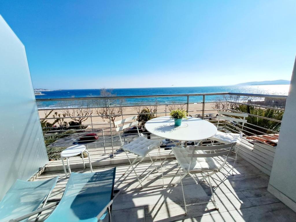 een balkon met een tafel en stoelen en het strand bij Le Panorama in Fréjus
