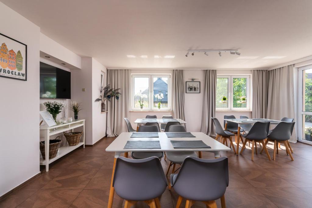 jadalnia ze stołami, krzesłami i oknami w obiekcie Sleeply Pensjonat Złotniki- dom dla 18 osób we Wrocławiu