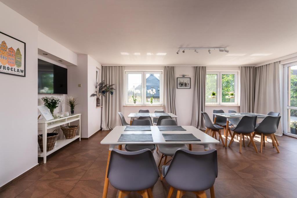a dining room with tables and chairs and windows at Sleeply Pensjonat Złotniki- dom dla 18 osób in Wrocław