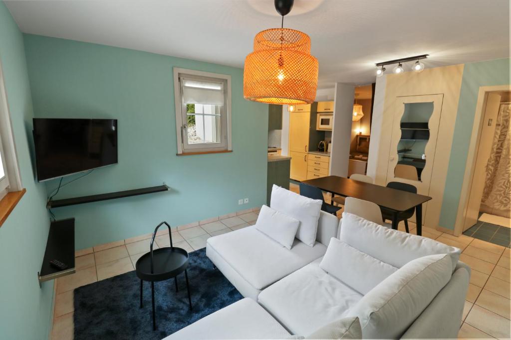 Appartement paisible avec terrasse في Domdidier: غرفة معيشة مع أريكة بيضاء وطاولة