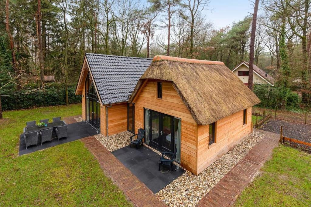 a small log cabin with a thatch roof at Luxe, sfeervol en vrijstaand boshuis Chalet LaMast in Norg