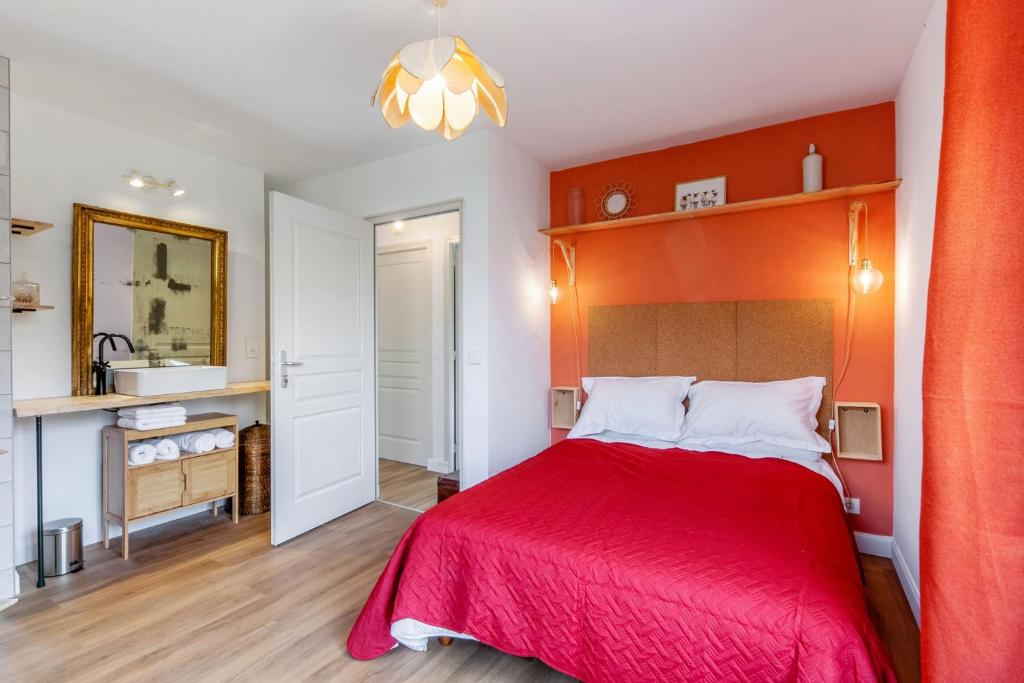 um quarto com uma cama vermelha e uma casa de banho em Gîte le 11 em Le Merlerault