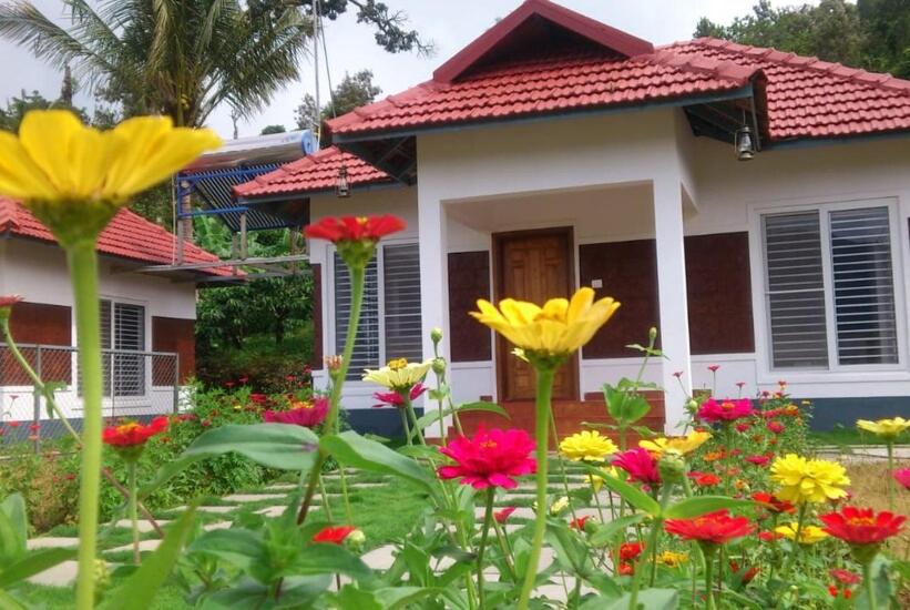 ein Haus mit Blumen davor in der Unterkunft Himani Heritage Resorts, formerly Camp Nishani Holidays in Madikeri