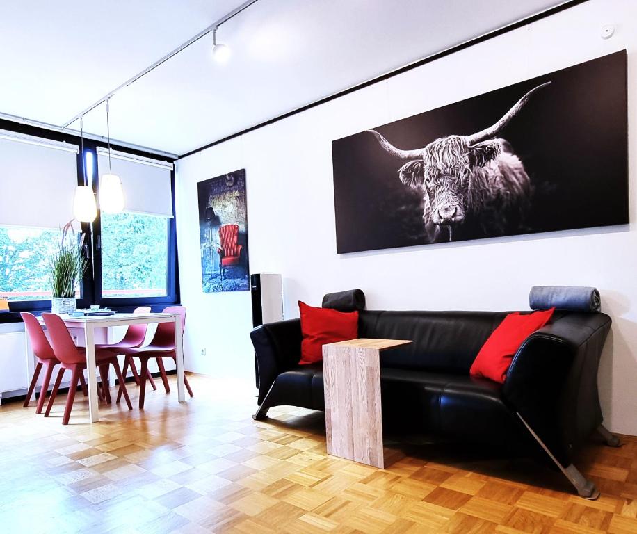 a living room with a black couch and a cow on the wall at Meer Glück am Steinhuder Meer in Wunstorf