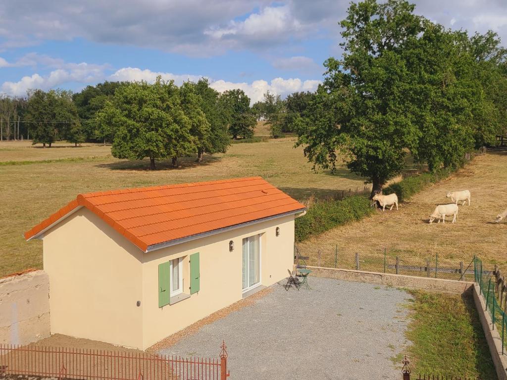 a small house with an orange roof in a field with cows at Tiny House moderne et son jardin privé - 5mn Roanne 