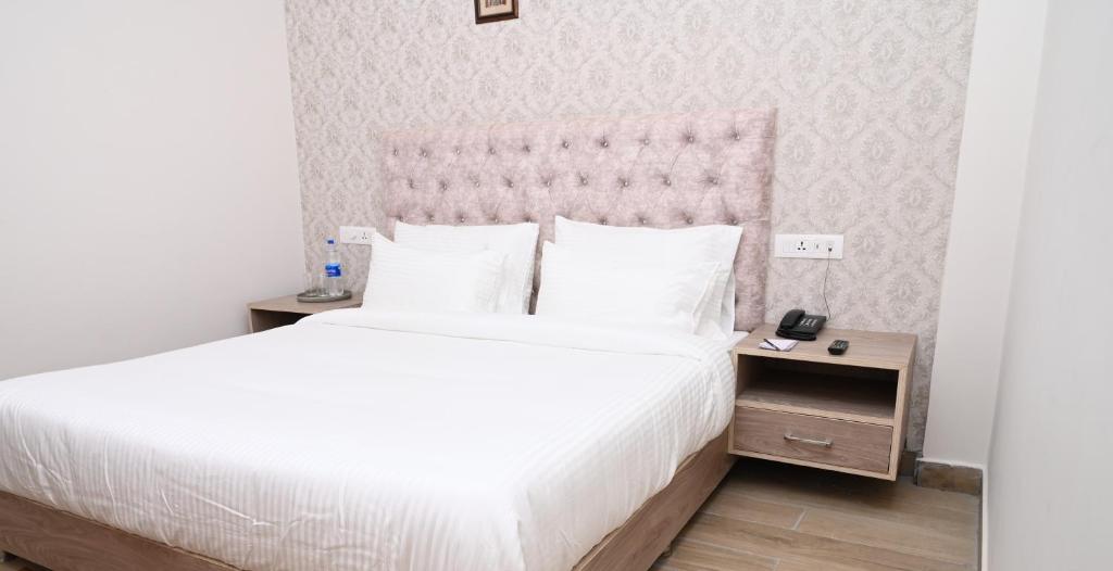 a bedroom with a white bed with a pink headboard at SPT Clarks Inn Suite, Mandi in Pāndoh