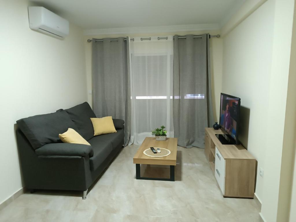 a living room with a black couch and a coffee table at Delicia, Sol y mar in Málaga