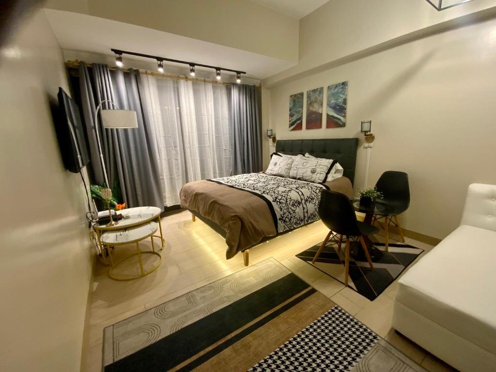 Schlafzimmer mit einem Bett, einem Tisch und Stühlen in der Unterkunft Gorgeous One Eastwood Ave Suite in Manila