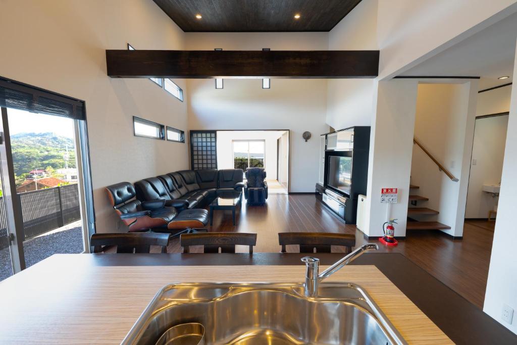 a kitchen with a sink and a living room at トワイライトヒルズ Twilight Hills in Motobu
