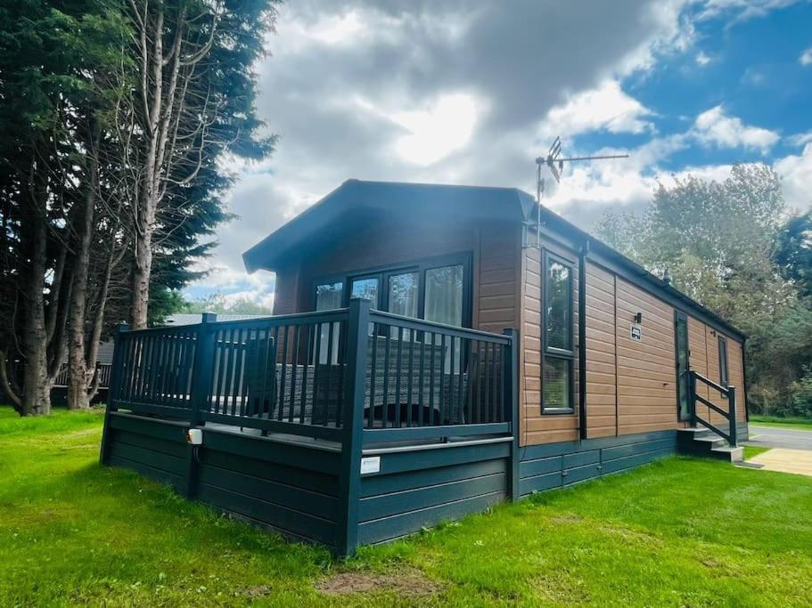 a tiny house with a deck on the grass at Hideaway Retreat with Hot Tub in York
