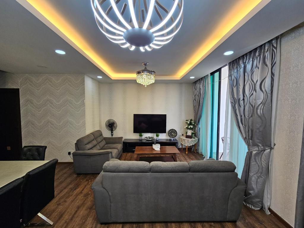 een woonkamer met een bank en een tv bij The Cozy Homestay @ Jazz Suite Vivacity Kuching in Kampong Tabuan