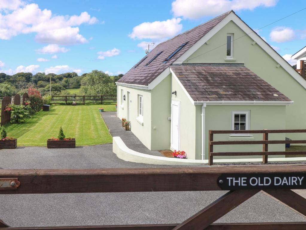 a small white house with a sign on a fence at The Old Dairy in New Moat