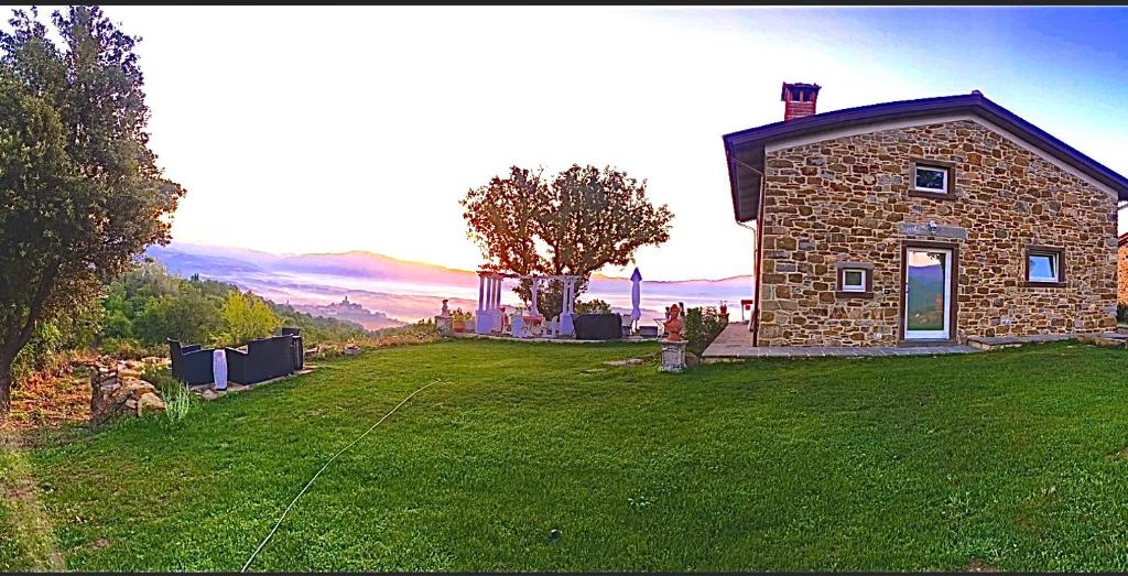 una casa de piedra en una colina con un patio verde en Villa Lux en Poppi