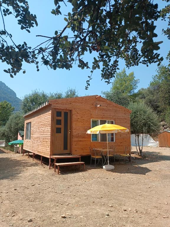 Cabaña pequeña con mesa y sombrilla amarilla en Eses Camping, en Muğla