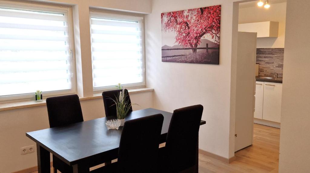 a dining room with a table and chairs and two windows at Sson-Appartments in Detmold