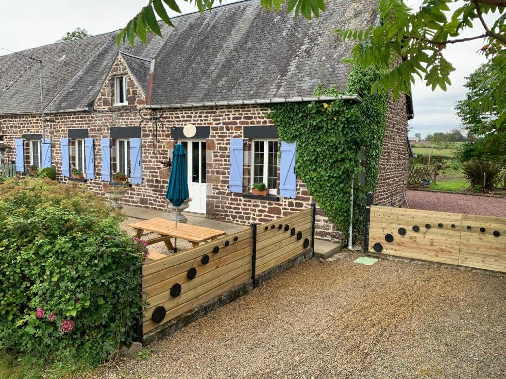 a brick house with a wooden fence in front of it at Gîte la belle etoile in Ver