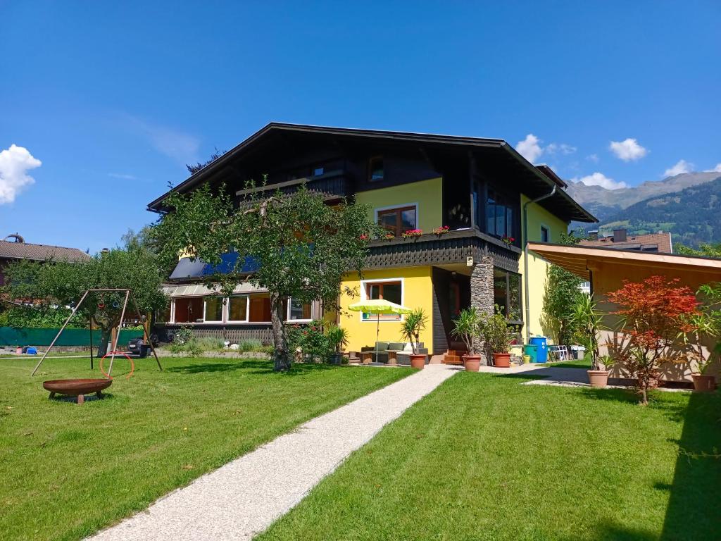 una casa con un cortile verdeggiante con parco giochi di Ferienwohnung Holiday Lienz a Lienz