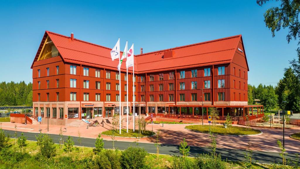 een rood gebouw met twee vlaggen ervoor bij Break Sokos Hotel Koli Kylä in Kolinkylä