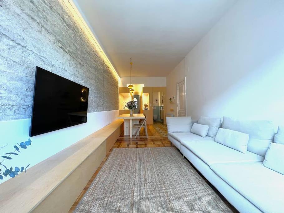 sala de estar con sofá blanco y TV de pantalla plana en VibesCoruña- Apartamento céntrico recién reformado, en A Coruña