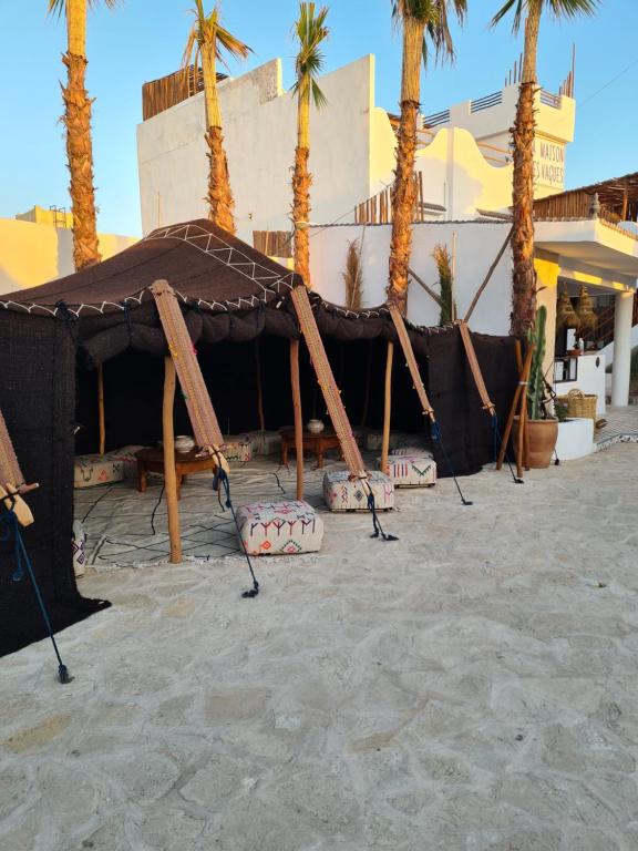 a tent on the beach with palm trees at La Maison des Vagues in Sidi Kaouki