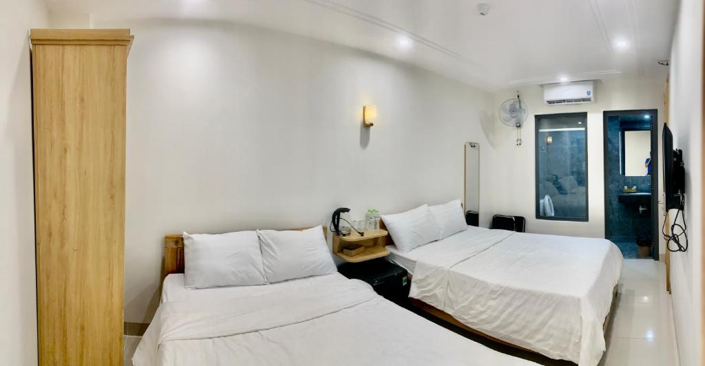 2 bedden in een kamer met witte lakens bij KHÁCH SẠN GIA HÒA 3 in Vung Tau
