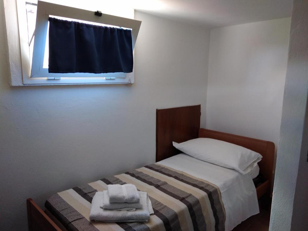 Schlafzimmer mit einem Bett und einem Fenster mit Handtüchern in der Unterkunft La Castagna Matta in Albareto