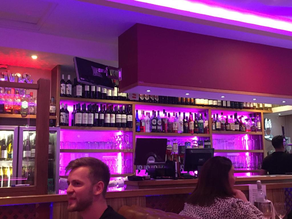 a man and woman sitting at a bar with purple lights at Ocean Breeze 5 minutes walk to the beach - Free Parking in Lancing