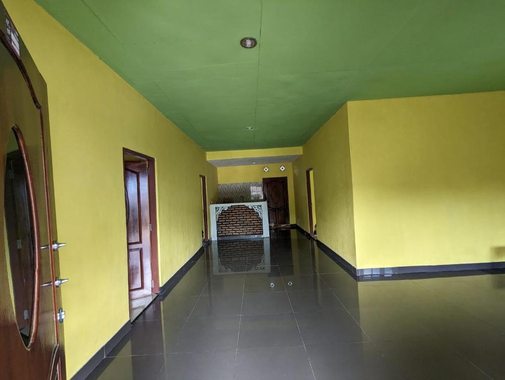 an empty room with yellow walls and a hallway at Mushtinal Guest House in Ende