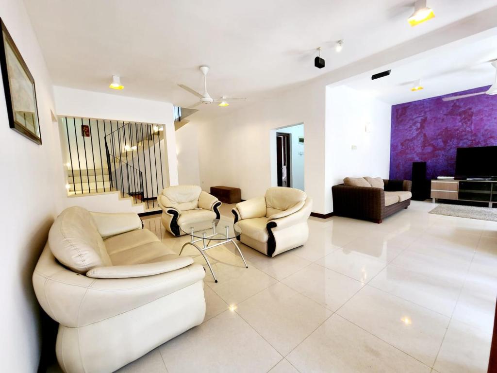 sala de estar con sillas blancas y TV en Luxury Haven: Spacious Two Bedroom Villa with Parking, en Piliyandala
