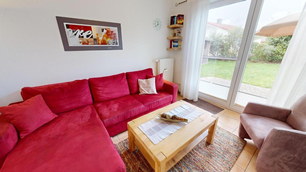 ペルツァーハケンにあるFeriendorf Südstrand Haus 04のリビングルーム(赤いソファ、コーヒーテーブル付)