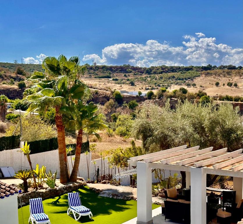 a patio with two lawn chairs and a palm tree at Casa-De-Golf in Alhaurín de la Torre