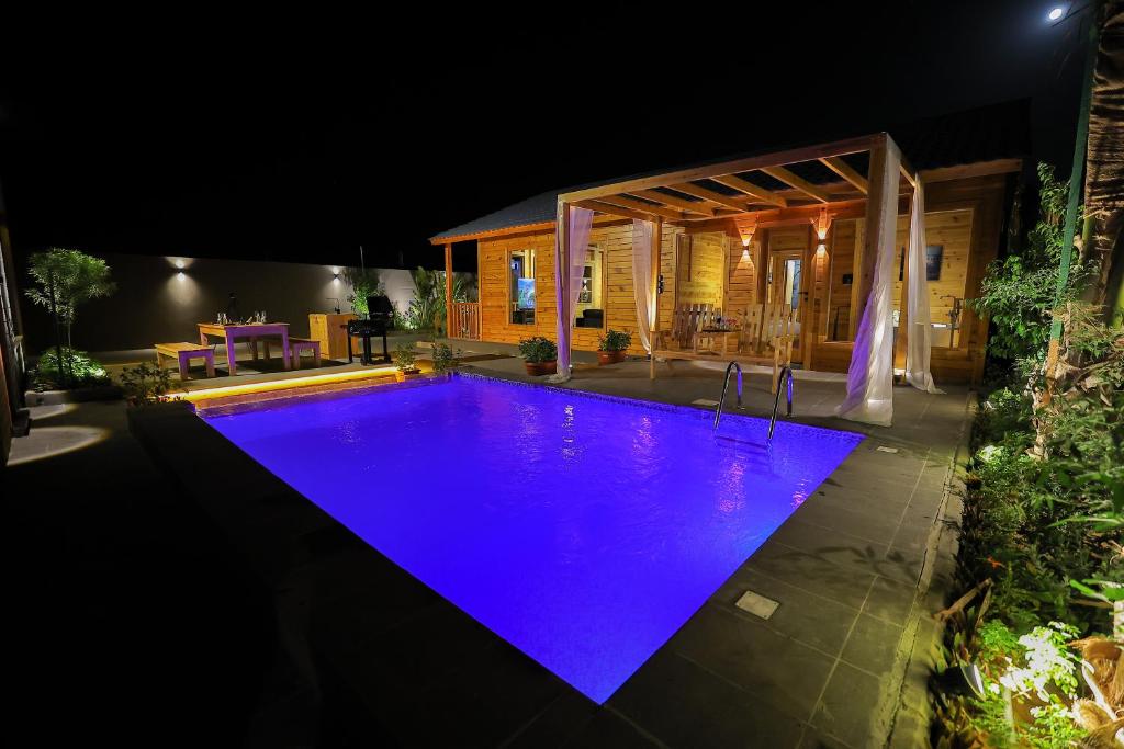 a swimming pool lit up at night in a house at منتجع المروج in Khalij Salman