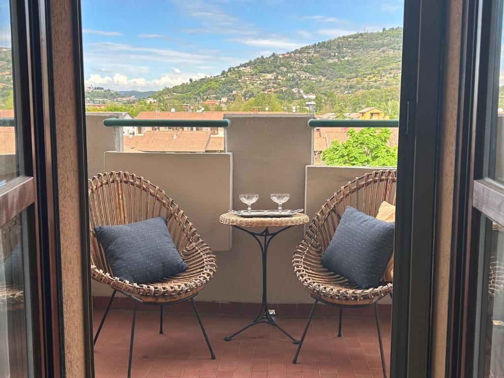 a balcony with two chairs and a table with wine glasses at Appartamento con vista in Brescia