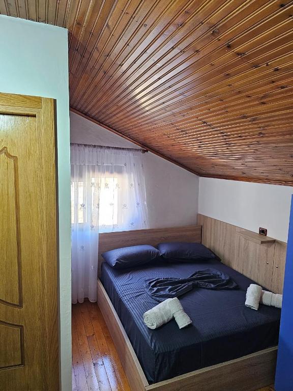 a bed in a room with a wooden ceiling at Castle - inside,Voga Guesthause in Krujë