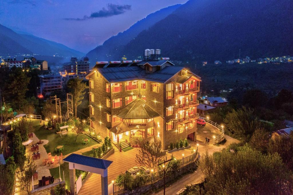 a large building with lights in a city at night at Montana Blues Resort by Snow City in Manāli